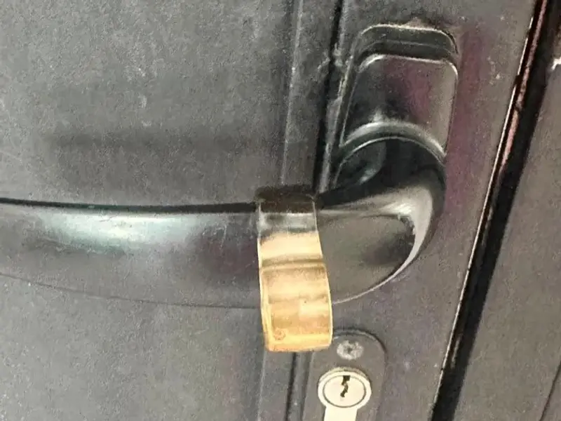 Bombín y manilla negra en una puerta metálica