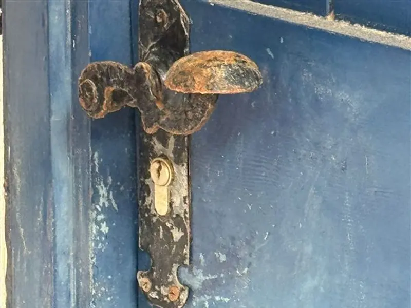Cerradura antigua con bombín en una puerta metálica azul