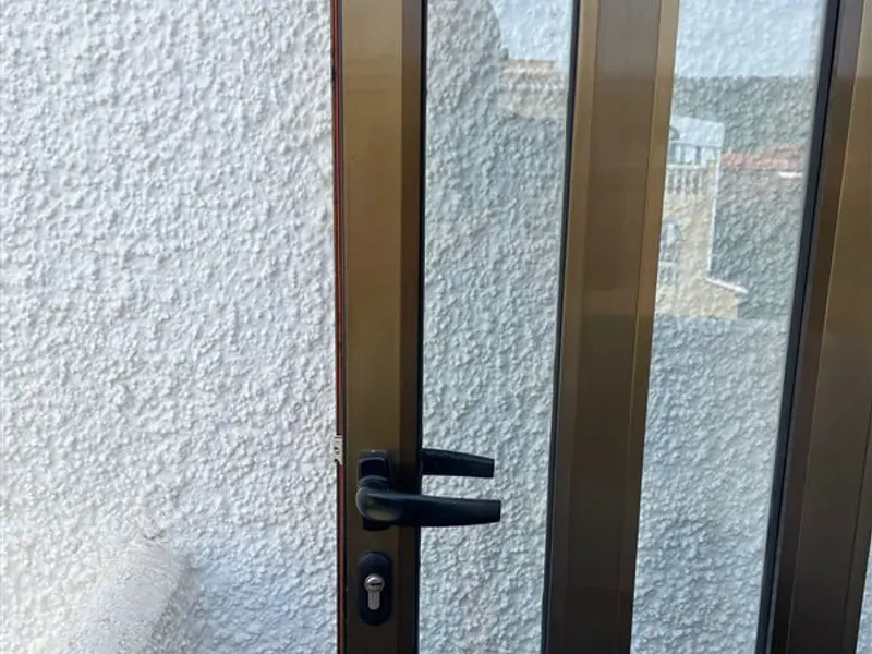 Puerta de aluminio con manilla y cerradura negras